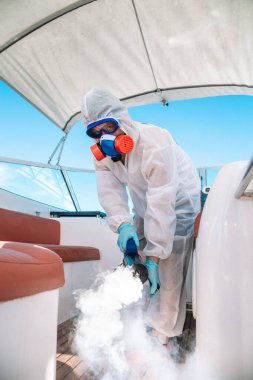  Özel üniformalı bir adam tekneyi dezenfekte eder.
