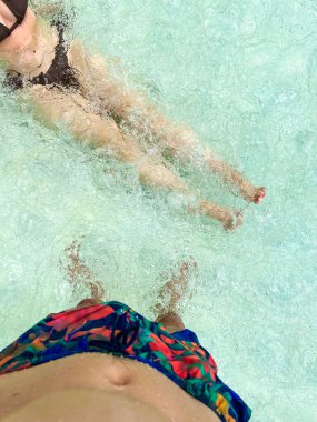 Havuzda yüzü olmayan bir adam ve bir kız. Şortlu bir adam ve mavi votkalı mayo giyen bir kız.