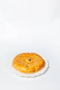 Beyaz bir yüzeyde altın kahverengi kabuklu lezzetli bir turta..