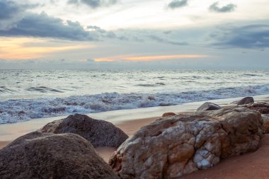 Sakin mavi sulara karşı ön planda deniz taşları olan güzel bir kıyı manzarası, seyahat ve doğa temaları için mükemmel..