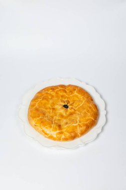 Beyaz bir yüzeyde altın kahverengi kabuklu lezzetli bir turta..