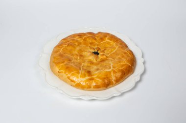 Beyaz bir yüzeyde altın kahverengi kabuklu lezzetli bir turta..