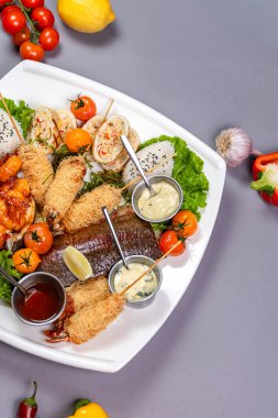 Izgara balık, baharatlı karides, börek ve beyaz tabakta pilav. Gri arkaplandaki üst görünüm - menü, yemek fotoğrafçılığı ve yemek servisi için mükemmel.