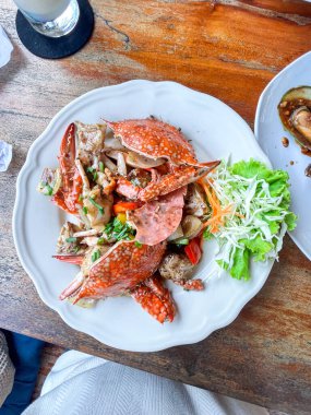 Beyaz tabakta yengeç ve soslu midye, üst manzara. Yengeçli yemekler ve soslu midyeler restoranda beyaz tabakta deniz ürünleri.