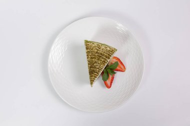 Çilekli ıspanaklı cheesecake dilimi ve beyaz arka planda nane şekeri.