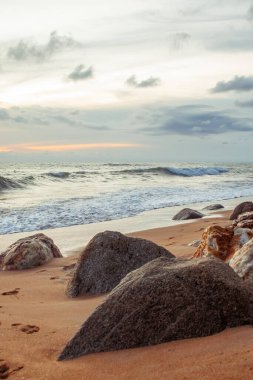 Sakin mavi sulara karşı ön planda deniz taşları olan güzel bir kıyı manzarası, seyahat ve doğa temaları için mükemmel..