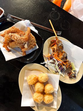 Çıtır karides, mısır topu ve tabakta ızgara ahtapot. Asyalı aperatifler siyah masada servis ediliyor. Yüksek kalite fotoğraf