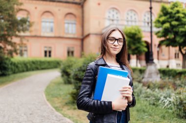 Sırt çantası ve ayakta ve parkta gülümsüyor not defterleri neşeli çekici genç kadın