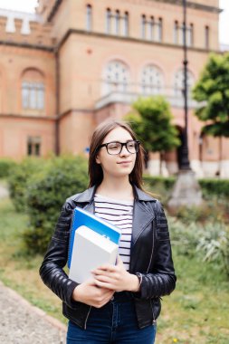 Notebook açık havada tutarak ve gülümseyen kız öğrenci