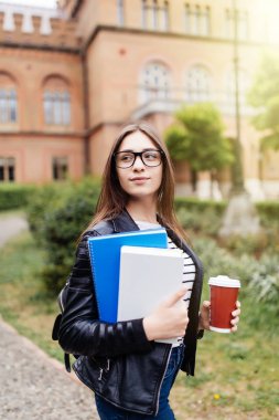Yazdırma alanı ile kampüste kahve ve kitap çanta ile gülümseyen Amerikan Üniversitesi Öğrenci