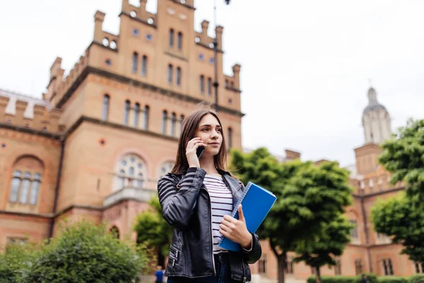 A pretty, young woman on the college campus talking on phone