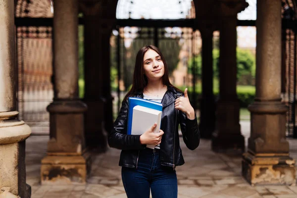 Açık havada yukarı gösteren gülümseyen bir kız öğrencinin portresi
