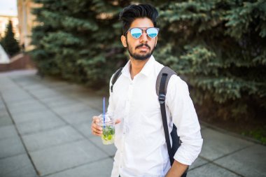 Portre portre, mutlu yakışıklı delikanlı içki soğuk içecek mojito güneşli bir günde caddenin üzerinde