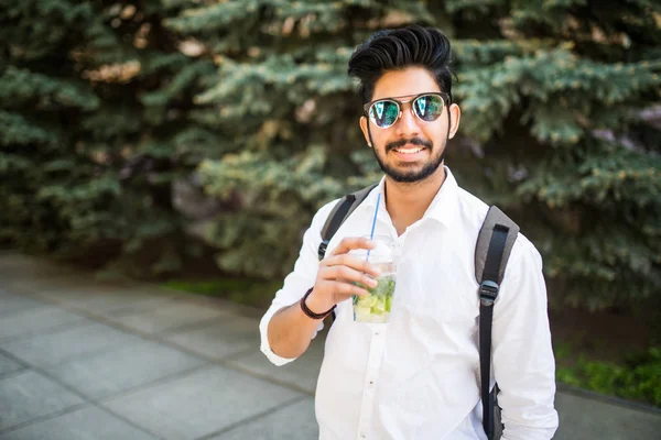 Güneş gözlüklü Genç Hintli adam portresi sokaklarda açık havada yaz içki mojito içmek