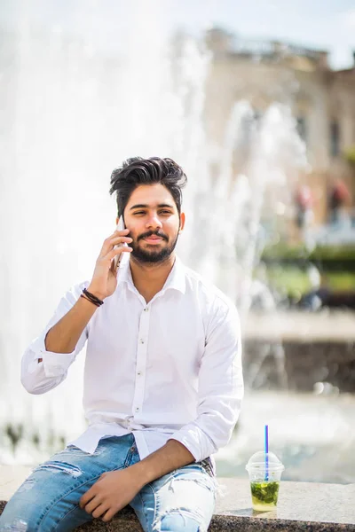 Joven Indio Joven Sentado Cerca Fuente Hablando Teléfono Con Mojito — Foto de Stock