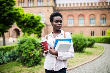 Eğitim, teknoloji ve insan kavramı - gülümseyen kadın Afrikalı-Amerikalı öğrenci ile çanta ve take away kahve fincanı