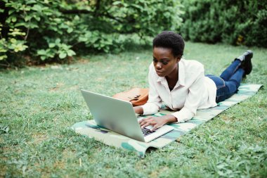 gülen sıradan öğrenci üniversite kampüsünde notlar alarak çim üzerinde yalan