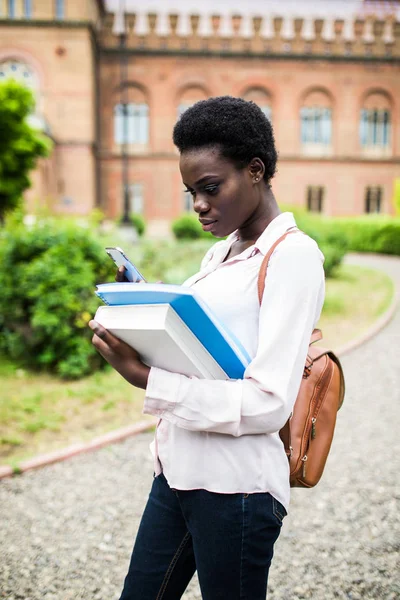 Cep telefonu kullanarak mutlu genç Afro-Amerikan Üni öğrenci