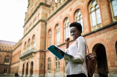 genç bir kız öğrenci kitaplığı atamalar yapıyor görüntü kadar yakın. ders notları alarak afro Amerikalı kadın.