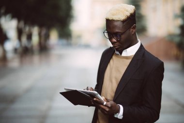 Yakışıklı Afro Amerikalı adam dijital tablet kullanma ve şehir yürüyüş sırasında gülümseyen