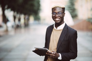 Yakışıklı Afro Amerikalı adam dijital tablet kullanma ve şehir yürüyüş sırasında gülümseyen