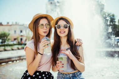 İki genç kadın renkli kokteyller sokakta içme.