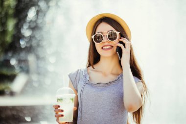 Mojito lezzetli güneşli sokak kokteyl serinletici ve telefonu konuşurken içme güzel ve genç birbayan. Taze meyve suyu. Kadın bir yaz gününde rahatlatıcı. Hareket eden aygıt. Akıllı telefon