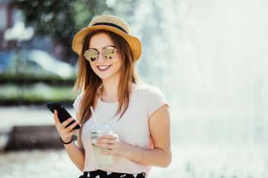 Genç güzel esmer kadın sokak telefonda yazarak oturan bir soğuk içecek ile