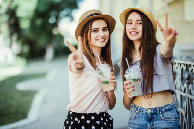 Todether kokteyl ile sokakta yürürken ve barış hareketi açık havada gösterilen bir selfie alarak iki neşeli kız