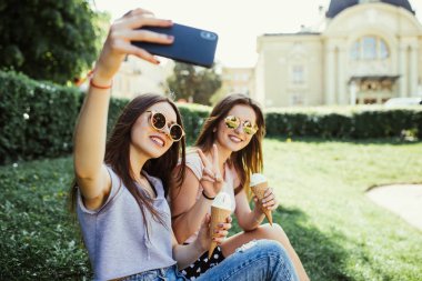 Yaz aylarında gün batımında nehir kenarında dondurma yerken selfie iki kadın arkadaş al