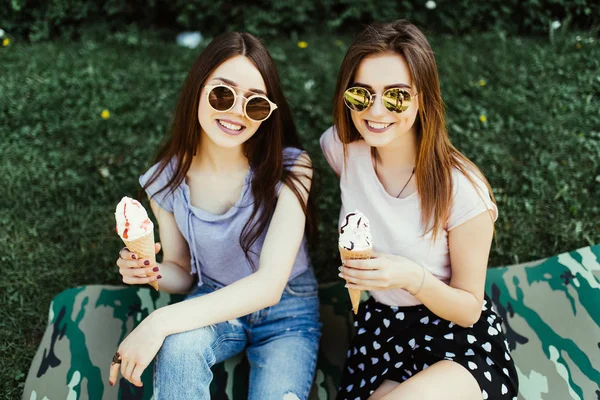 Birlikte dondurma şehir sokak çimlere oturup yemek iki genç kadının portresi.