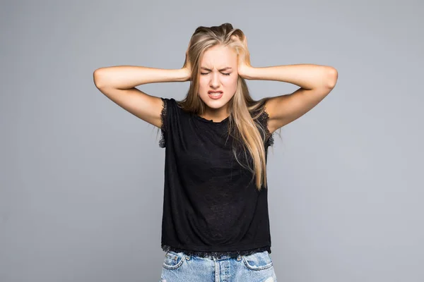 Portrait of a angry stressed woman covering ears with palms and shouting isolated on the gray background