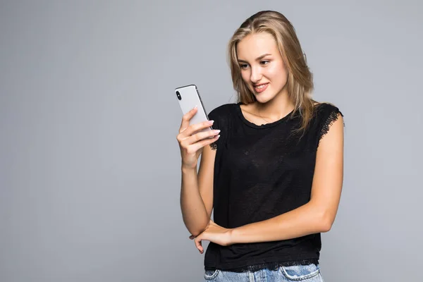 Улыбается Прекрасная Молодая Женщина Стоящая Использующая Мобильный Телефон Сером Фоне — стоковое фото