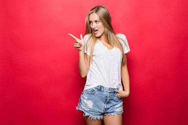 Kırmızı zemin üzerine işaret gösteren bir kadın. Mutlu kırmızı arka plan üzerinde sunulması gülümseyen çok taze ve enerjik güzel genç kız.