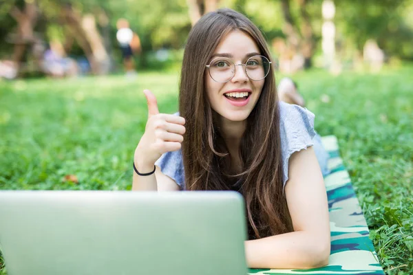 Счастливая Брюнетка Очках Лежит Траве Парке Ноутбуком Показывает Большой Палец — стоковое фото