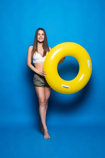 Woman in summer wear with inflatable ring isolated over blue background