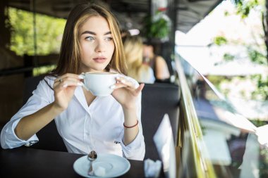 Sabahları restoranda kahve içen bir kadın.