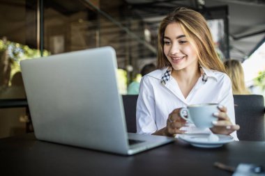 kahveyle siting ve kafede dizüstü kullanan kadın
