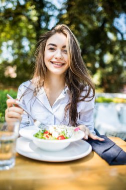 Genç kadın cafede karışık sebze salatası yiyor