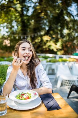 Genç kadın cafede karışık sebze salatası yiyor