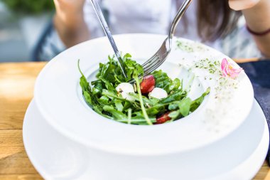 Kafede öğle yemeğinde bir fincan kahve ile sebze salatası yemek için çatal ve kaşık tutan çekici kadın el kapatın. Sağlıklı ve vejetaryen gıda.