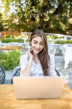 bir dizüstü bilgisayar ile bir kafede oturan genç ve çekici bir kadın