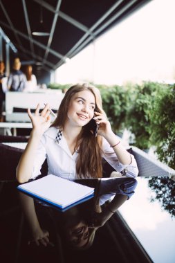 Şık öğrenci arkadaşıyla telefonda konuşmak ve bazı raporlar kafe havada oturup Not Defteri'nde belirterek trendy şapkalı. Telefon görüşmesi sırasında bilgi yazma yaratıcı hippi kız duydum