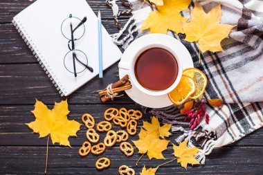 Sonbahar kompozisyon, yaprakları sonbaharda, sıcak buharlı fincan çay ve sıcak bir eşarp ahşap masa arka plan üzerinde.