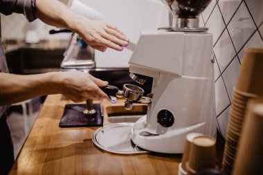 Seçilen odak profesyonel barista kahve pounder ahşap sapı ile kullanarak basarak ellerinde.
