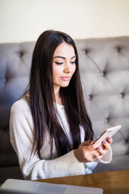 Kahve dükkanı ve kullanır smartphone masada oturan genç kadın