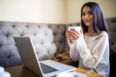 Modern cafe bar içinde laptop ile otururken çalışan güzel kadın