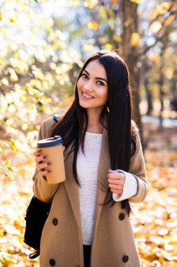 Sonbahar kadın sonbahar şehir parkında kahve içme. Tek kullanımlık kahve fincan sıcak içecek keyfi kız.