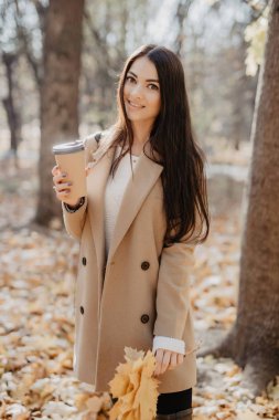 Güzel kadın içme kahve altında sonbahar park yeşillik düşmek. Altın Sonbahar park