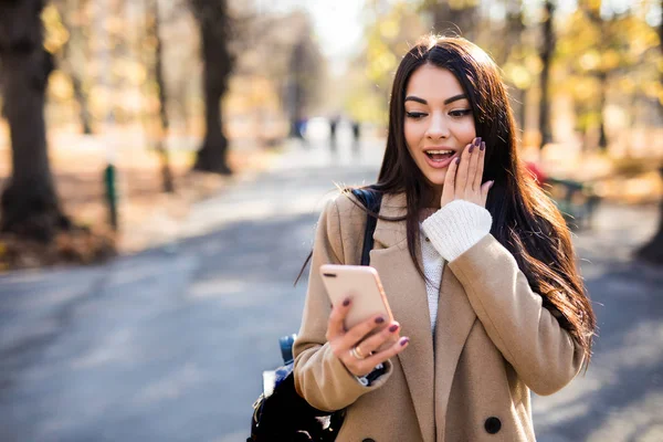 Vacker Ung Kvinna Som Förvånad Läs Mobiltelefon Klädd Höstkappa Utomhus — Stockfoto